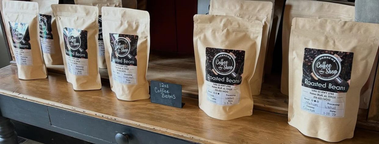 Kraft paper bags of Hebrews fresh-roasted coffee beans lined up on a wooden counter
