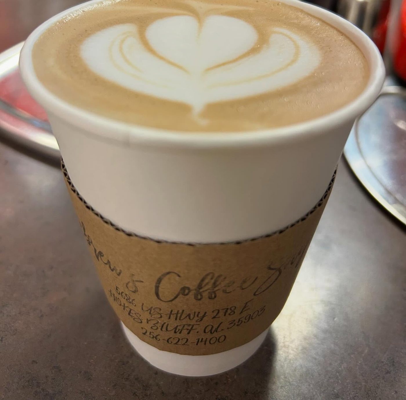 A hot latte with heart latte art in a Hebrews cup